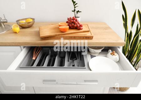 Offene Schublade mit Besteck und Obst auf der Theke in der Küche Stockfoto