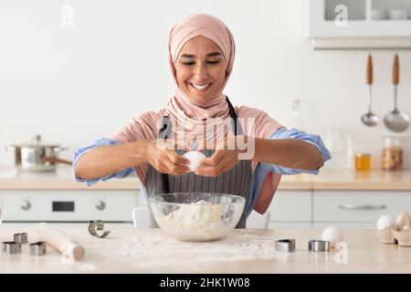 Porträt Einer Schönen Lächelnden Islamischen Frau In Hijab Backen In Der Küche Stockfoto