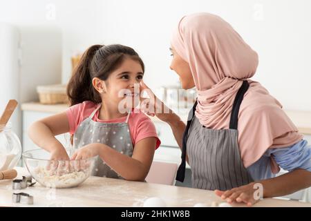 Mutter Tochter Freizeit. Glücklich Islamische Mutter Und Nette Weibliche Kind Backen Zusammen Stockfoto