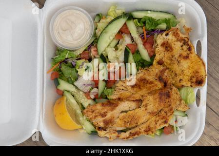 Blick von oben auf die Bestellung von gegrilltem Hähnchensalat, der die Styropor-Box komplett füllt. Stockfoto