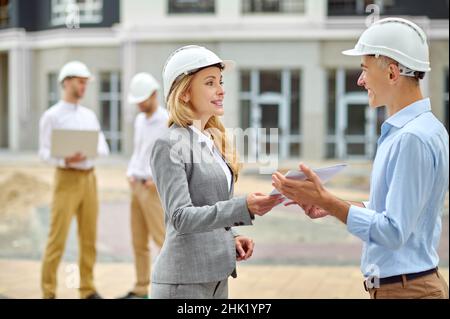 Der Inspektor übergibt die Gebäudedokumentation an einen leitenden Ingenieur Stockfoto