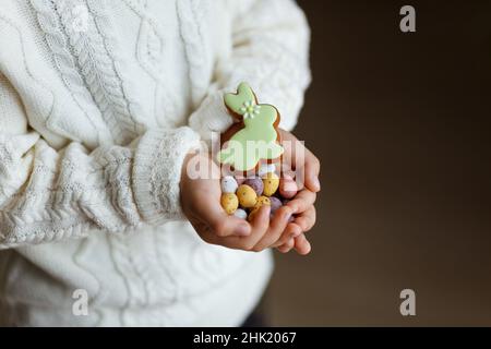 Kleiner Junge mit schokoladenöstereiern und Häschen in den Händen. Stockfoto