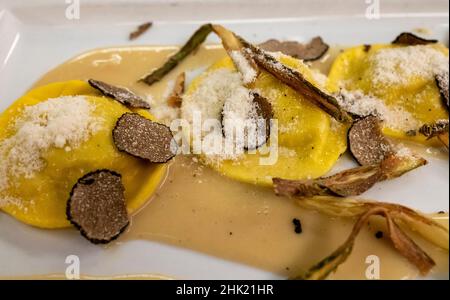 Italienische Küche, frisch hausgemachte rote Kartoffel gefüllte Pasta Tortellacci oder Ravioli Knödel mit Sommer schwarzen Trüffel und knusprigen grünen Spargel und geriebt Stockfoto