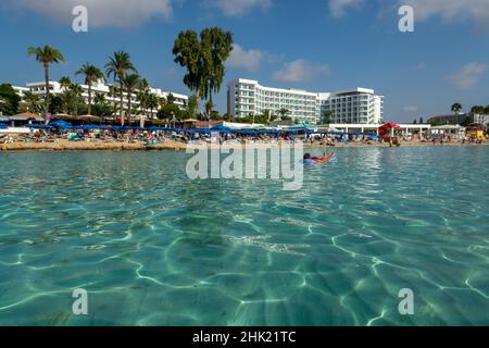 Kristallklares blaues Wasser des Mittelmeers am weißen Sandstrand von Nissi in Ayia Napa, Zypern Stockfoto