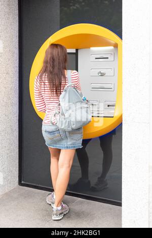 Anonyme weibliche Reisende, die in der Stadt einen Geldautomaten benutzen Stockfoto