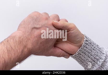 Draufsicht auf die Hand einer Frau, die die Hand eines älteren Mannes auf weißem Hintergrund hält. Konzept Freundschaft der Generation Stockfoto