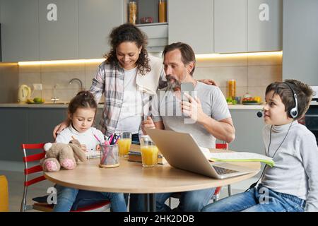 Familie schaut sich die Tochter an, die in der Küche malt Stockfoto