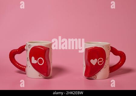 Zwei paarige Tassen mit der Aufschrift Liebe und Griffe in Form von Herzen Stockfoto