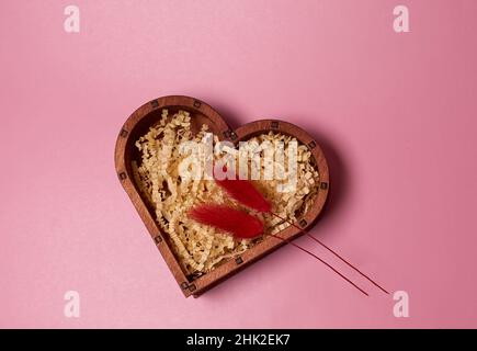 Geschenkschachtel aus Holz in Herzform und zwei rot getrocknete Blumen Stockfoto