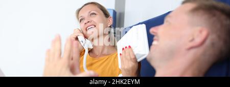 Die Frau telefoniert, während sie mit dem Mann im Hotelzimmer auf dem Bett liegt Stockfoto