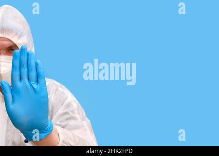 Arzt in Schutzanzug-Uniform mit Schutzbrille und medizinischer Gesichtsmaske auf einem Studio-blauen Hintergrund, Kopierraum Stockfoto