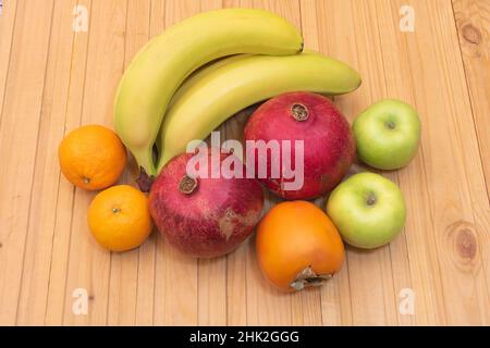 Gute Gesundheit exotische Früchte auf Holz Hintergrund wie Bananen Mandarinen Granatäpfel Äpfel und Kaki. Stockfoto