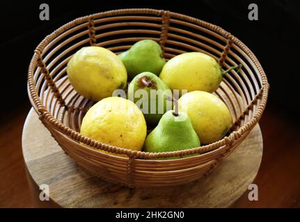 Ein Obstkorb mit Birnen und Zitronen - ein Korb voller Grün und Gold. Die Zitronen sind selbst erwachsen Stockfoto