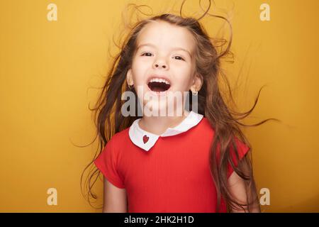 Nettes kleines Mädchen, das ihr ein strahlendes Lächeln auf das Gesicht zaubert, begleitet von ihrer Schönheit, die die Welt wie ein Sonnenstrahl erleuchtet. Stockfoto