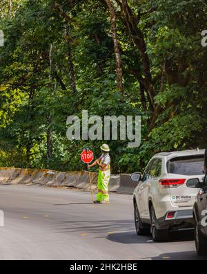 Ein Bauarbeiter, der den Verkehr stoppt, hält ein Stoppschild in der Hand. Stockfoto