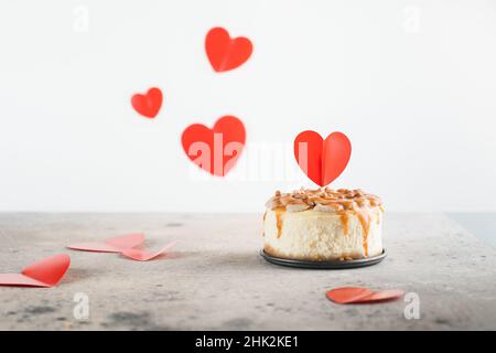 Kleiner Bento-Käsekuchen mit kleinem Herztopper. Valentinstag-Konzept. Muttertag, Geburtstag Kuchen Karte Hintergrund. Speicherplatz kopieren Stockfoto