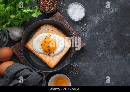 Spiegeleier auf gebratenem Toast auf schwarzem Hintergrund. Draufsicht, Kopierbereich. Stockfoto