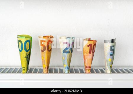 Geld für die Heizung Batterie. Euro-Banknoten in einem Heizkörper, das Konzept der teuren Heizkosten. Stockfoto