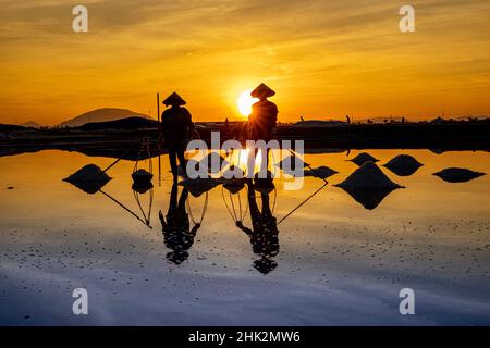 Vietnam. DOC Lassen Sie Salzsee. Arbeiter ernten das Salz. Sonnenaufgang am frühen Morgen. Stockfoto