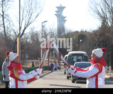 Peking, China. 2nd. Februar 2022. Fackellauf Song Luzeng (R) übergibt die Flamme an Fackellauf Zuo Zhiyong während des Olympischen Fackellaufs 2022 in Peking im Olympischen Waldpark in Peking, der Hauptstadt Chinas, am 2. Februar 2022. Quelle: Jia Haocheng/Xinhua/Alamy Live News Stockfoto