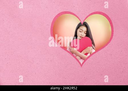 Asiatische Frau, die ein rotes Herz mit einem traurigen Ausdruck hält. Valentinstag Stockfoto