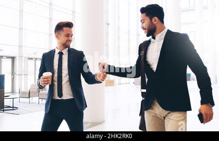 Hey, Kumpel. Eine kurze Aufnahme von zwei hübschen jungen Geschäftsleuten, die sich tagsüber im Büro begrüßten. Stockfoto