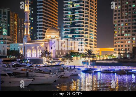 Nachtansicht des Wolkenkratzers des Wohnviertels in Dubai Marina und Yachten, die in der Nähe des Pier in der Abendbeleuchtung festgemacht wurden. Nachts. Urlaub In Stockfoto