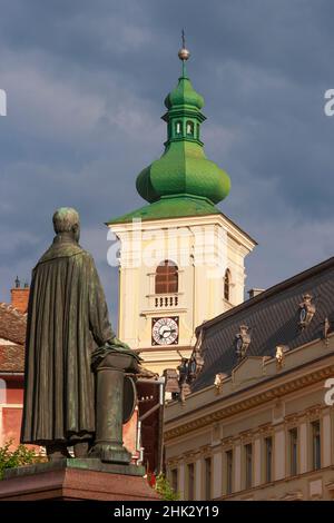 Sibiu, Siebenbürgen, Rumänien. Die Statue des lutherischen Bischofs Georg Daniel Teutsch steht vor dem Kirchturm der römisch-katholischen Kirche der Heiligen Dreifaltigkeit. Stockfoto