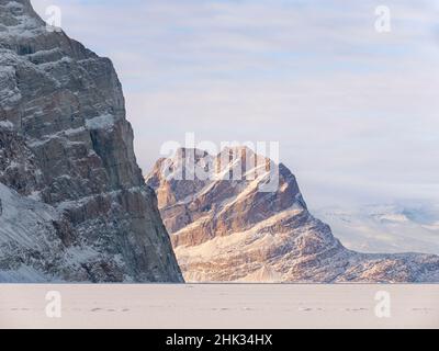 Eisberge wurden im Winter im Meereis des Uummannaq-Fjordsystems eingefroren, die Insel Uummannaq im Hintergrund. Grönland, Dänisches Territorium Stockfoto
