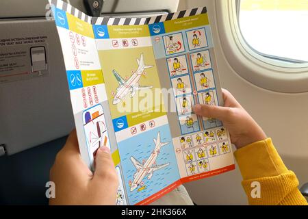 Lviv, Ukraine - September, 2021 : Teenager lesen SkyUp Airlines Flugsicherheitsanweisungen an Bord. Selektiver Fokus Stockfoto