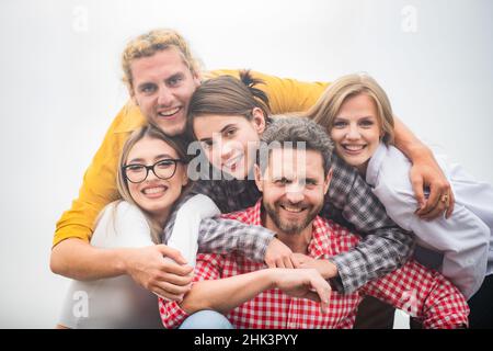 Lächelnde Gruppe von Freunden lachend. Eine Gruppe von Freunden umarmen sich gemeinsam im Freien. Fröhliche, multirassische Menschen lachen zusammen, glücklich, vielfältig und jung Stockfoto