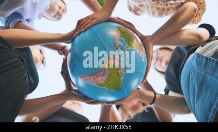 Freundinnen halten einen Globus in der Mitte des Kreises. Stockfoto