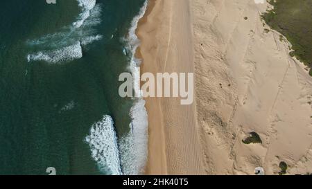 Reifenspuren im Sand entlang eines unberührten australischen Strandes hinterlassen. Stockfoto