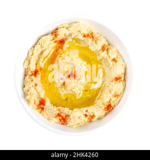 Hummus Dip mit Paprikapulver und Olivenöl, in einer weißen Schüssel. Nahost-Dip, Aufstrich oder herzhaftes Gericht aus gekochten, pürierten Kichererbsen. Stockfoto