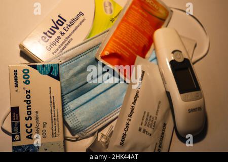 Bern, Schweiz, 05. Januar 2022: Medizinische Maske, klinisches Thermometer und Fieber, Grippe und kalte Medikamente. Stockfoto