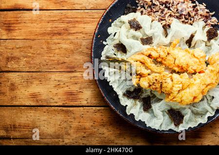 Gebratener Seebarschfisch mit Reis auf Reispapier. Geröstete Meeresfrüchte. Speicherplatz kopieren Stockfoto