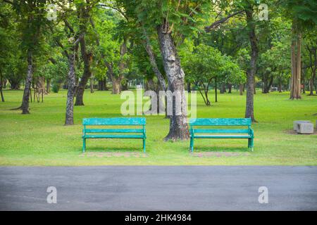 Zwei grüne Bänke unter Bäumen im Park, damit sich die Menschen auf Reisen, beim Sport und anderen im öffentlichen Park entspannen können Stockfoto
