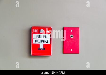Feueralarm-Presse-Maschine und Feuerwehrmann-Telefonbuchse, die an Betonwand im Gebäude installiert Stockfoto