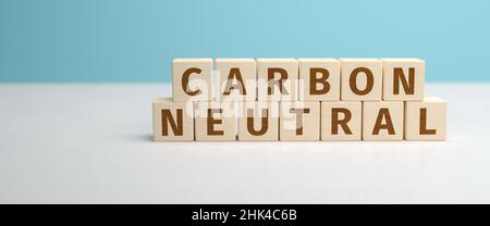 CO2 Reduktionskonzept. Holzspielzeugwürfel bilden die Worte Carbon Neutral. Türkisblauer Hintergrund. Webbanner-Format. Stockfoto