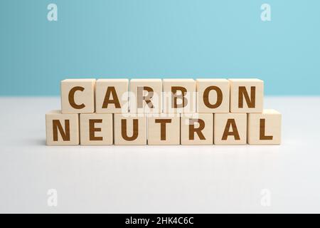 CO2 Reduktionskonzept. Holzspielzeugwürfel bilden die Worte Carbon Neutral. Türkisblauer Hintergrund. Stockfoto