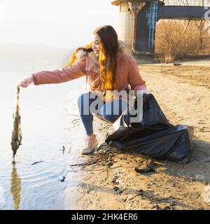 Junge Frau säubert das Wasser aus Plastikmüll Stockfoto