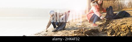 Zwei junge Freiwillige säubern den Strand von verschiedenen Müll Stockfoto