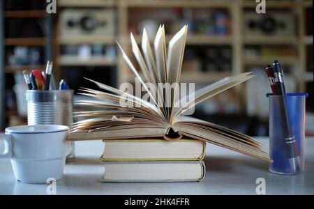 Home Office, Bildung, Business, Konzept mit offenem Buch, Kaffee und Büromaterial, Nahaufnahme mit geringer Schärfentiefe. Stockfoto