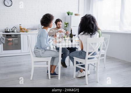 Multiethnische Freunde, die während des Mittagessens Pasta essen Stockfoto