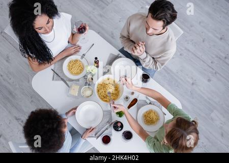 Draufsicht auf multiethnische Freunde, die zusammen zu Mittag essen Stockfoto