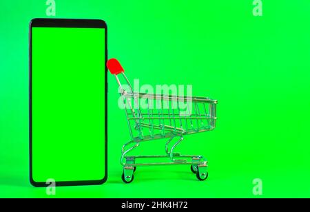 Konzept der Lieferung, Online-Lebensmittel-Shopping. Metall leeren Warenkorb auf grünem Hintergrund. Stockfoto