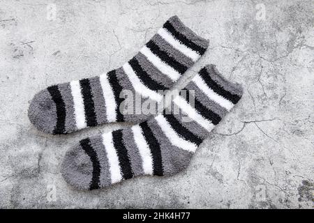 Ein Paar Wintersocken mit grauem Streifen auf grauem Hintergrund. Stockfoto