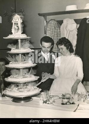 Hochzeit in Italien am 1950s: Die Braut und der Bräutigam im Restaurant schneiden den Kuchen Stockfoto