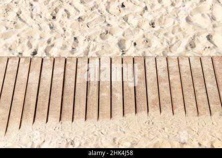 Natürlicher, farbiger Holzsteg führt über den Sandstrand, Hintergrundstruktur Stockfoto