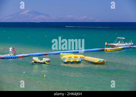 Zakynthos, Griechenland - 15. August 2016: Touristen wandern auf dem blauen schwimmenden Pier aus Kunststoff mit festgetäuten Vergnügungsbooten. Banana Beach, griechische Insel Zakynthos, Stockfoto